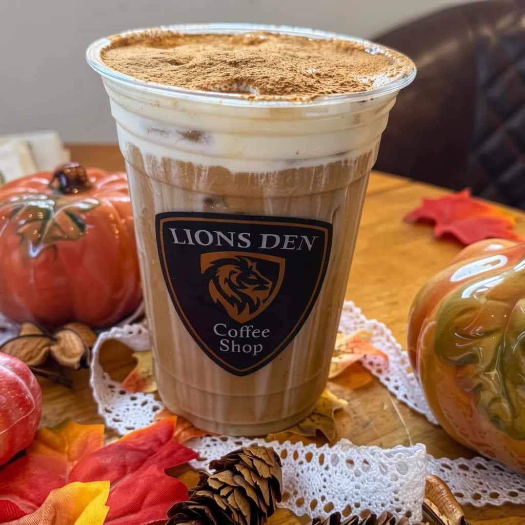 Iced coffee dusted with cinnamon among pumpkins and autumn leaves