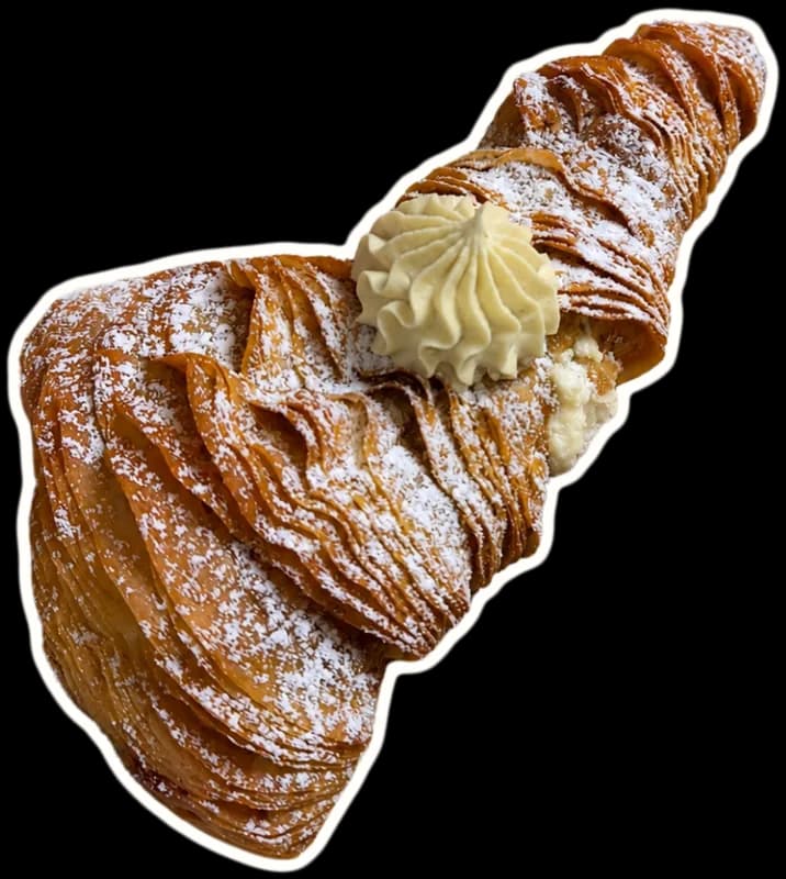 A sfogliatella with crisp, flaky layers, a swirl of piped cream and a dusting of powdered sugar